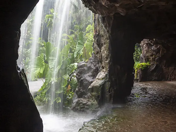 411144 - Water spray at a waterfall in front of a dark rock grotto