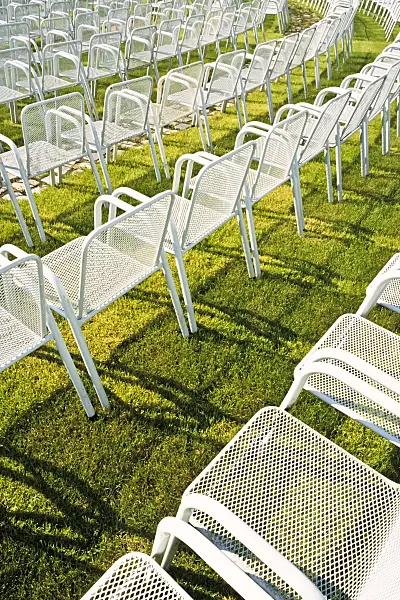 391003 - White metal chairs in several long rows on a lawn