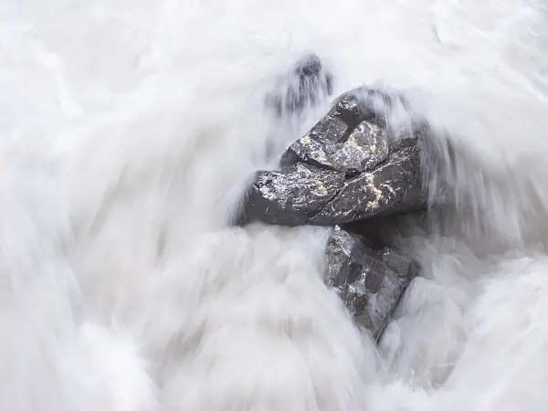 439164 - White spray over boulders of a falling mountain stream