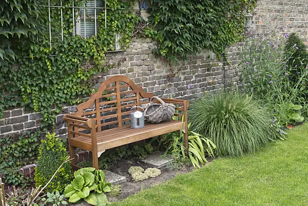 536195 - Wooden bench with watering can and basket in a perennial garden